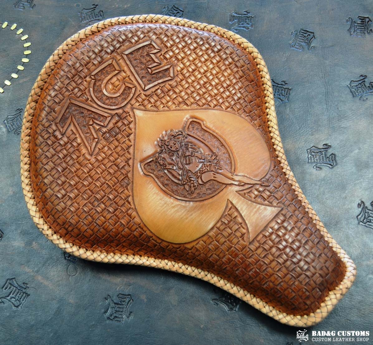 "ACE Pin-Up Girl" design hand tooled and braided on a chopper solo seat. Veg tan leather with kangaroo lace.