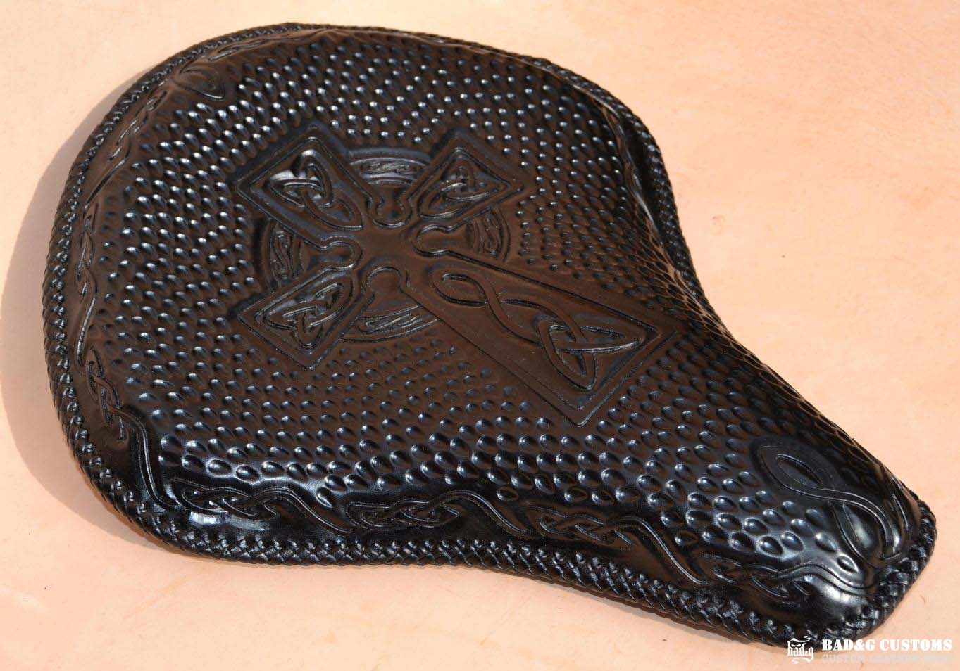 "CROSS" design hand tooled and braided on a chopper solo seat. Black Veg tan leather with kangaroo lace.