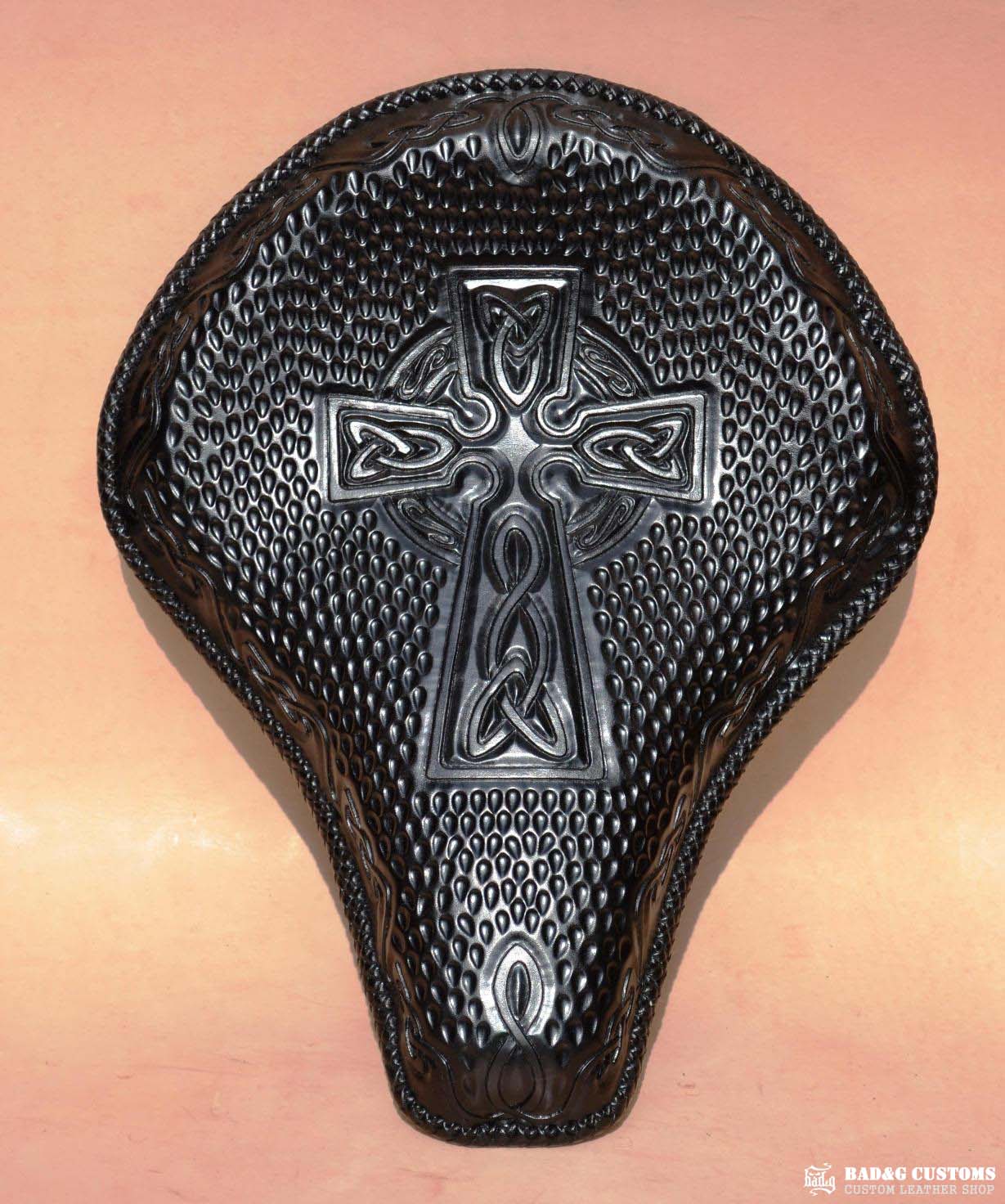 "CROSS" design hand tooled and braided on a chopper solo seat. Black Veg tan leather with kangaroo lace.